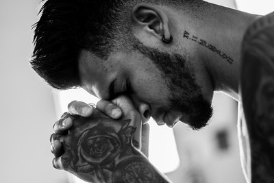 hombre con tatuajes rezando